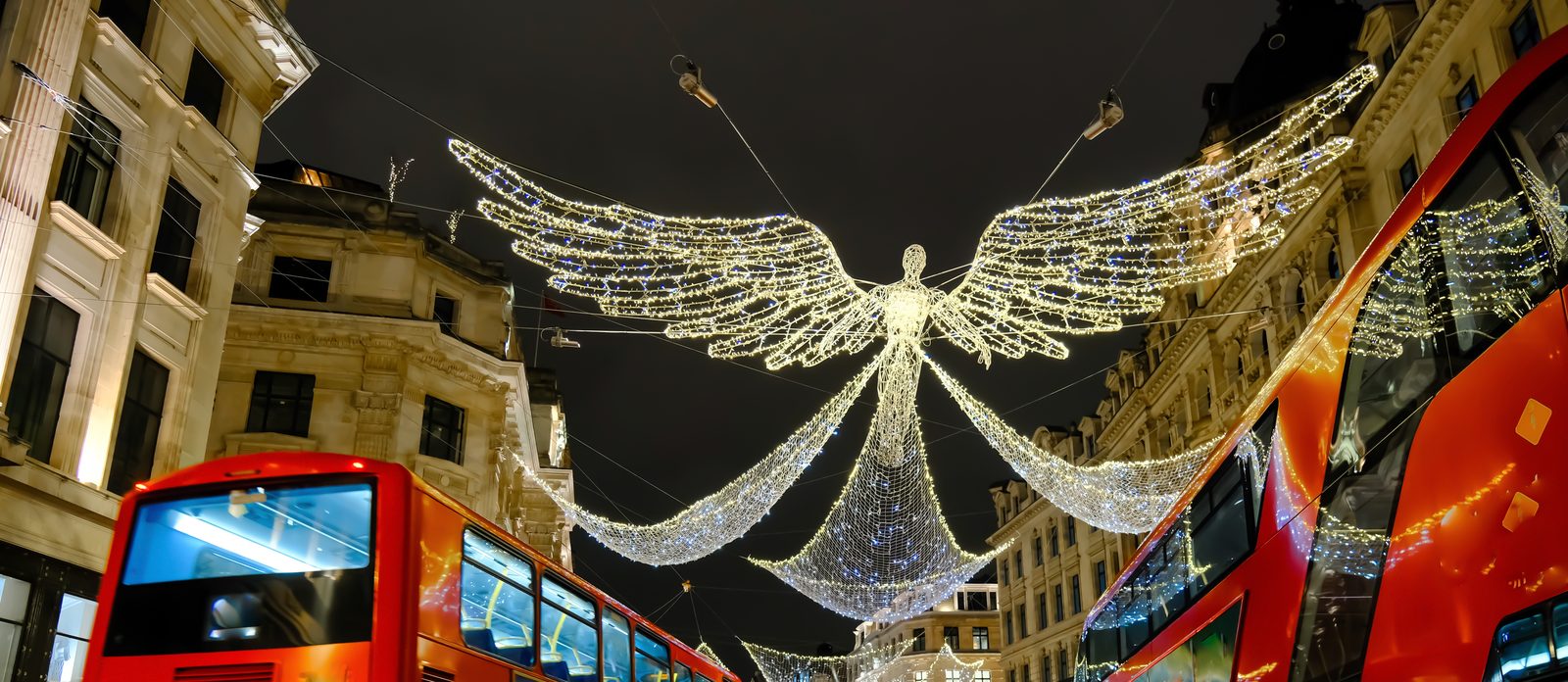 Ángeles de luz sobre Regent Street y autobuses rojos de dos pisos en Navidad, Londres