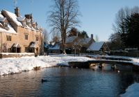 El río helado de Bourton-on-the-Water entre casas de piedra nevadas.