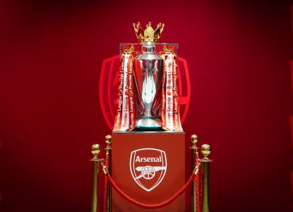 El trofeo de la Premier League expuesto junto al escudo del Arsenal.