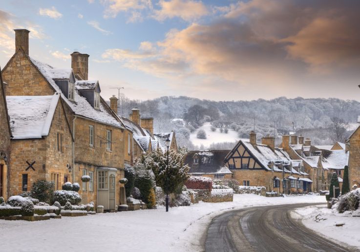 Casas de piedra de un pueblo de los Cotswolds nevado al atardecer.