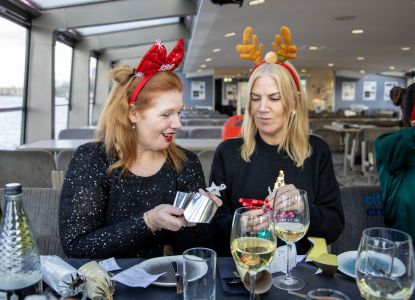Dos pasajeras abriendo un regalo durante el almuerzo de Navidad a bordo.