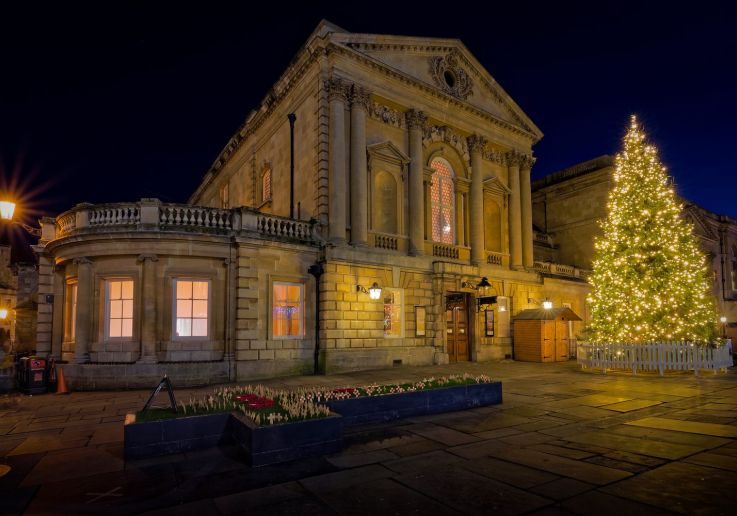 Un edificio histórico de Bath iluminado junto a un gran árbol de Navidad.