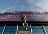 Fachada del estadio de Wembley con el cartel de bienvenida y la estatua de Bobby Moore
