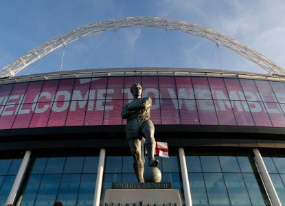 Fachada del estadio de Wembley con el cartel de bienvenida y la estatua de Bobby Moore