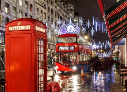Una cabina telefónica roja y un autobús londinense rodeados de luces navideñas.