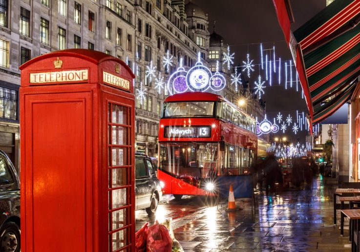 Una cabina telefónica roja y un autobús londinense rodeados de luces navideñas.