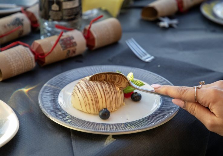 Postre navideño servido en la mesa junto a un cracker de Navidad.