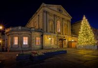 Un edificio histórico de Bath iluminado junto a un gran árbol de Navidad.