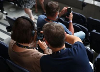 Visitantes con dispositivo multimedia en las gradas del Tottenham Hotspur Stadium