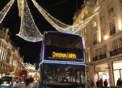 Autobús descubierto del tour de las luces navideñas circulando bajo la iluminación de Regent Street.