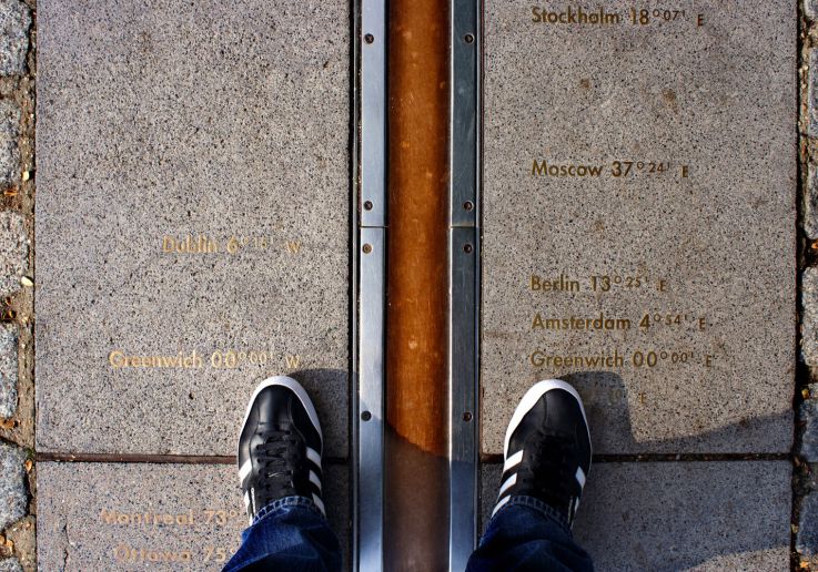 Visitantes con los pies a ambos lados del Meridiano Cero de Greenwich.