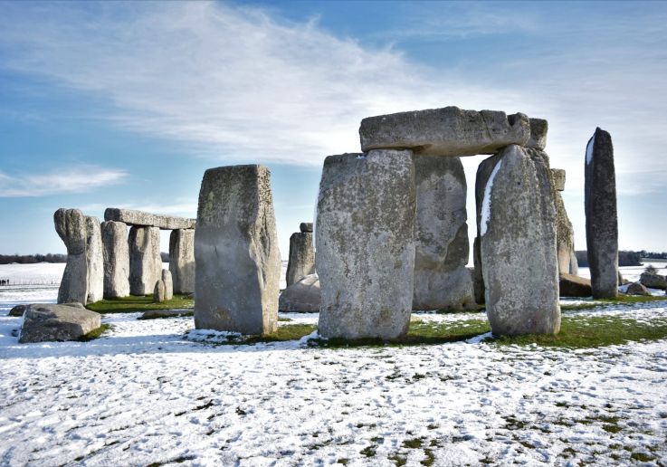 El círculo de piedras de Stonehenge rodeado de nieve bajo un cielo despejado.