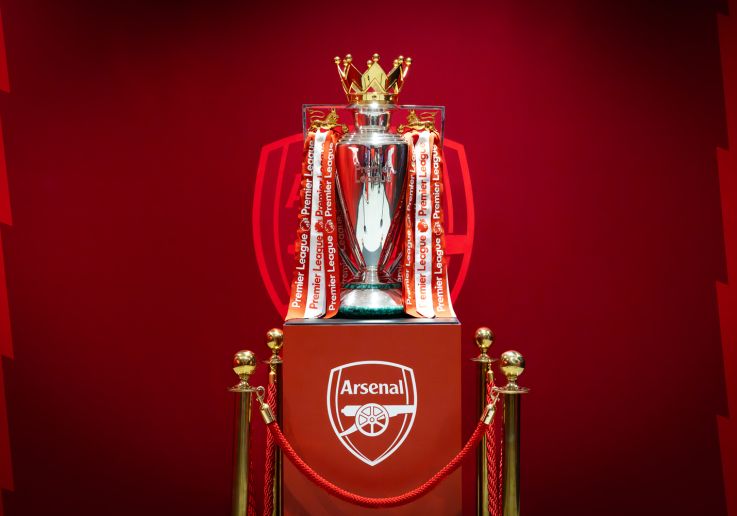 El trofeo de la Premier League expuesto junto al escudo del Arsenal.