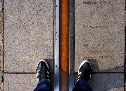 Visitantes con los pies a ambos lados del Meridiano Cero de Greenwich.