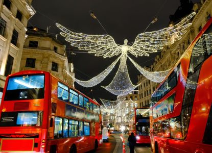 Autobuses rojos avanzando bajo los ángeles de luz de Regent Street.
