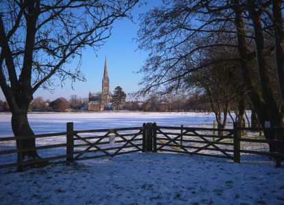Vista de la Catedral de Salisbury a través del parque cubierto de nieve.