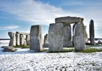 El círculo de piedras de Stonehenge rodeado de nieve bajo un cielo despejado.