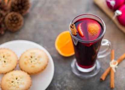 Mince pies y vino caliente especiado servidos con canela.
