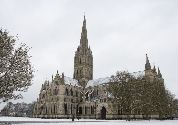 La catedral de Salisbury y su aguja gótica sobre el prado nevado.