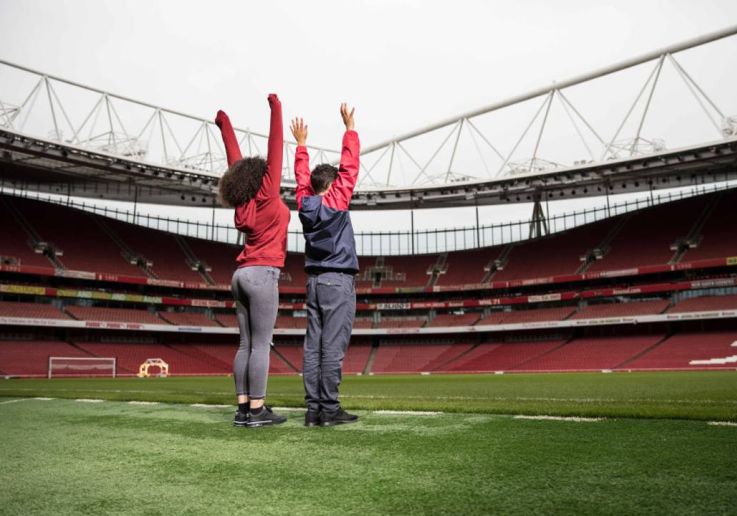 Dos visitantes descubren el terreno de juego durante el tour del estadio del Arsenal.