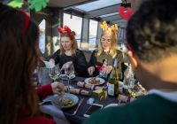 Comensales con diademas navideñas disfrutando del almuerzo mientras el barco navega.