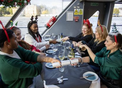 Grupo de pasajeros tirando de crackers alrededor de la mesa del crucero.