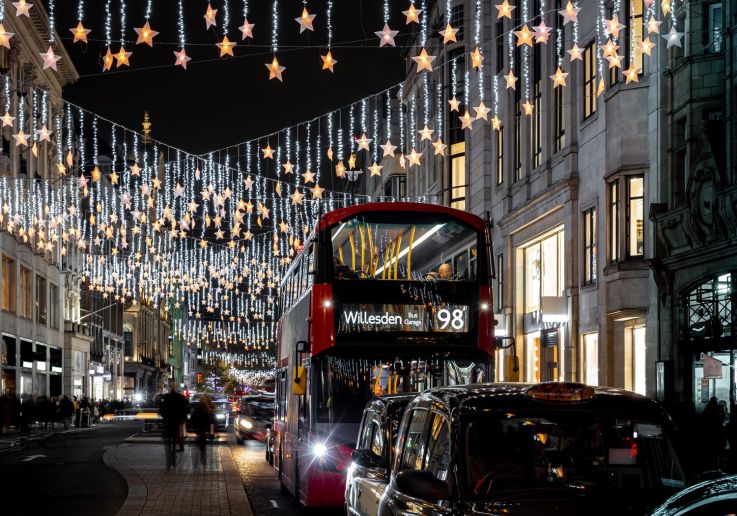 Cortinas de estrellas iluminadas sobre Oxford Street con un autobús rojo.