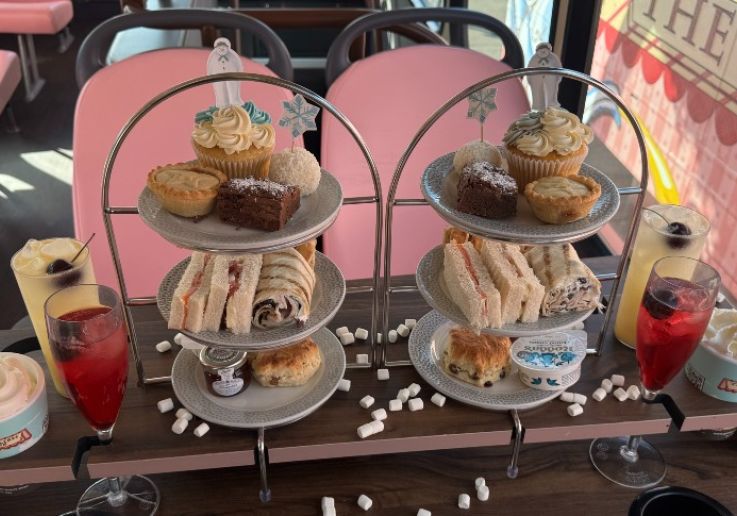 Alzada de pastas, scones y bollos con una bebida festiva junto a la ventanilla.