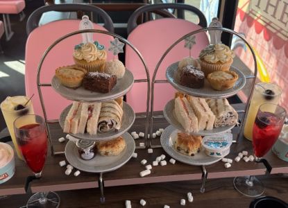 Alzada de pastas, scones y bollos con una bebida festiva junto a la ventanilla.