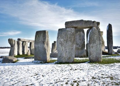 El círculo de piedras de Stonehenge rodeado de nieve bajo un cielo despejado.