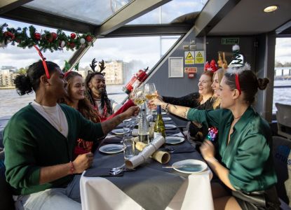 Pasajeros brindando y tirando de crackers navideños en la mesa del crucero.