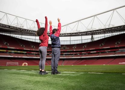 Dos visitantes descubren el terreno de juego durante el tour del estadio del Arsenal.