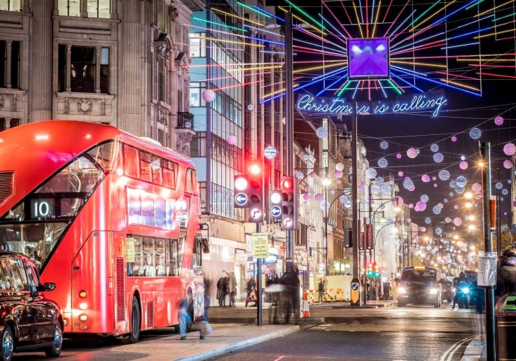 Un autobús rojo de dos pisos bajo las luces de «Christmas is calling» en Oxford Street.