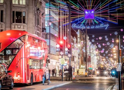 Un autobús rojo de dos pisos bajo las luces de «Christmas is calling» en Oxford Street.
