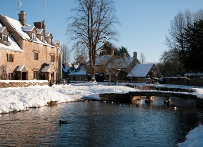 El río helado de Bourton-on-the-Water entre casas de piedra nevadas.