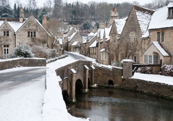 El puente y las casas medievales de Castle Combe cubiertos de nieve.