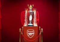 El trofeo de la Premier League expuesto junto al escudo del Arsenal.