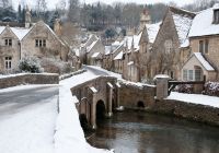El puente y las casas medievales de Castle Combe cubiertos de nieve.
