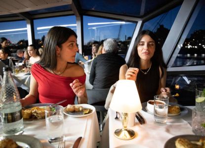 Comensales cenando a bordo con Londres iluminado al otro lado del ventanal