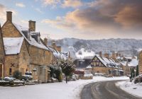 Casas de piedra de un pueblo de los Cotswolds nevado al atardecer.