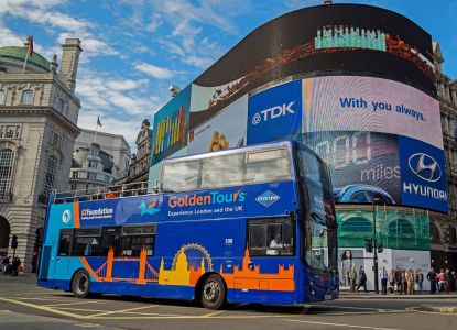 Autobús turístico de dos pisos frente a las pantallas luminosas de Piccadilly Circus.