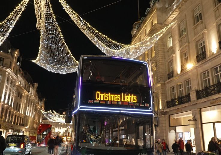 Autobús descubierto del tour de las luces navideñas circulando bajo la iluminación de Regent Street.