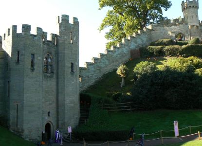 Una torre y la muralla del Castillo de Warwick sobre el montículo, iluminadas por el sol.
