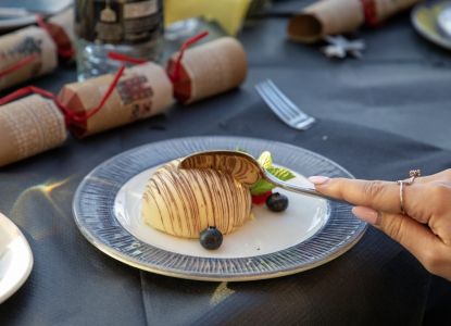 Postre navideño servido en la mesa junto a un cracker de Navidad.