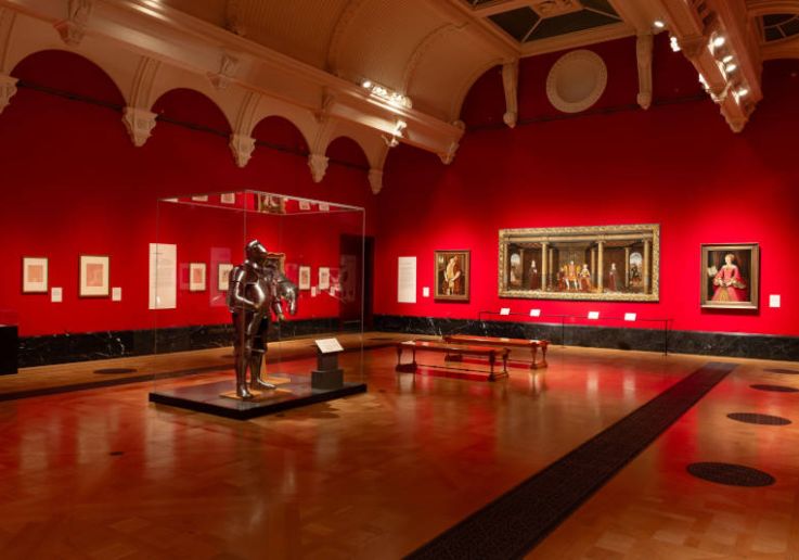 Sala de paredes rojas de la King's Gallery con una armadura y pinturas de la Royal Collection