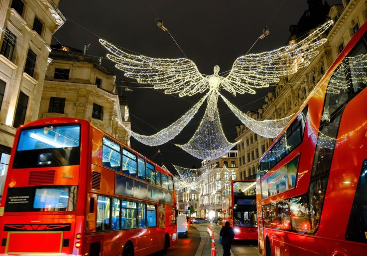 Autobuses rojos avanzando bajo los ángeles de luz de Regent Street.