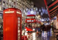 Una cabina telefónica roja y un autobús londinense rodeados de luces navideñas.